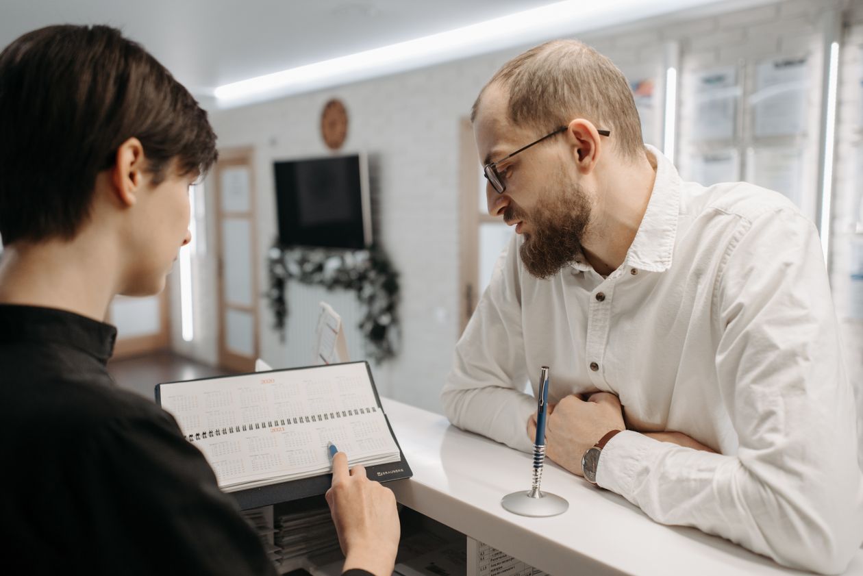 A receptionist reviews an appointment calendar with a customer at the front desk.