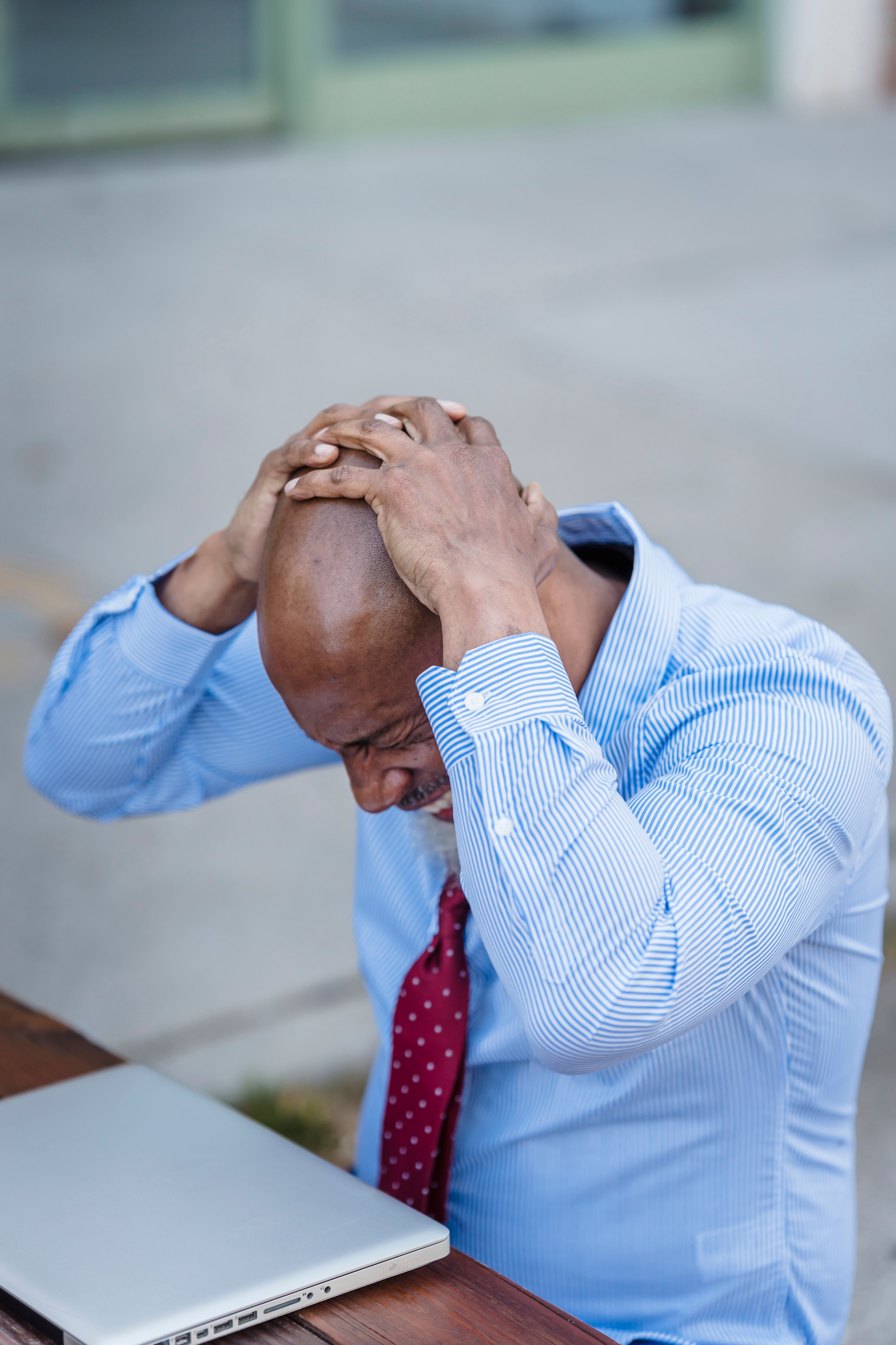 A businessman sits outdoors with his laptop, holding his head in frustration, representing the moment a small business owner realizes their website isn't working for them.